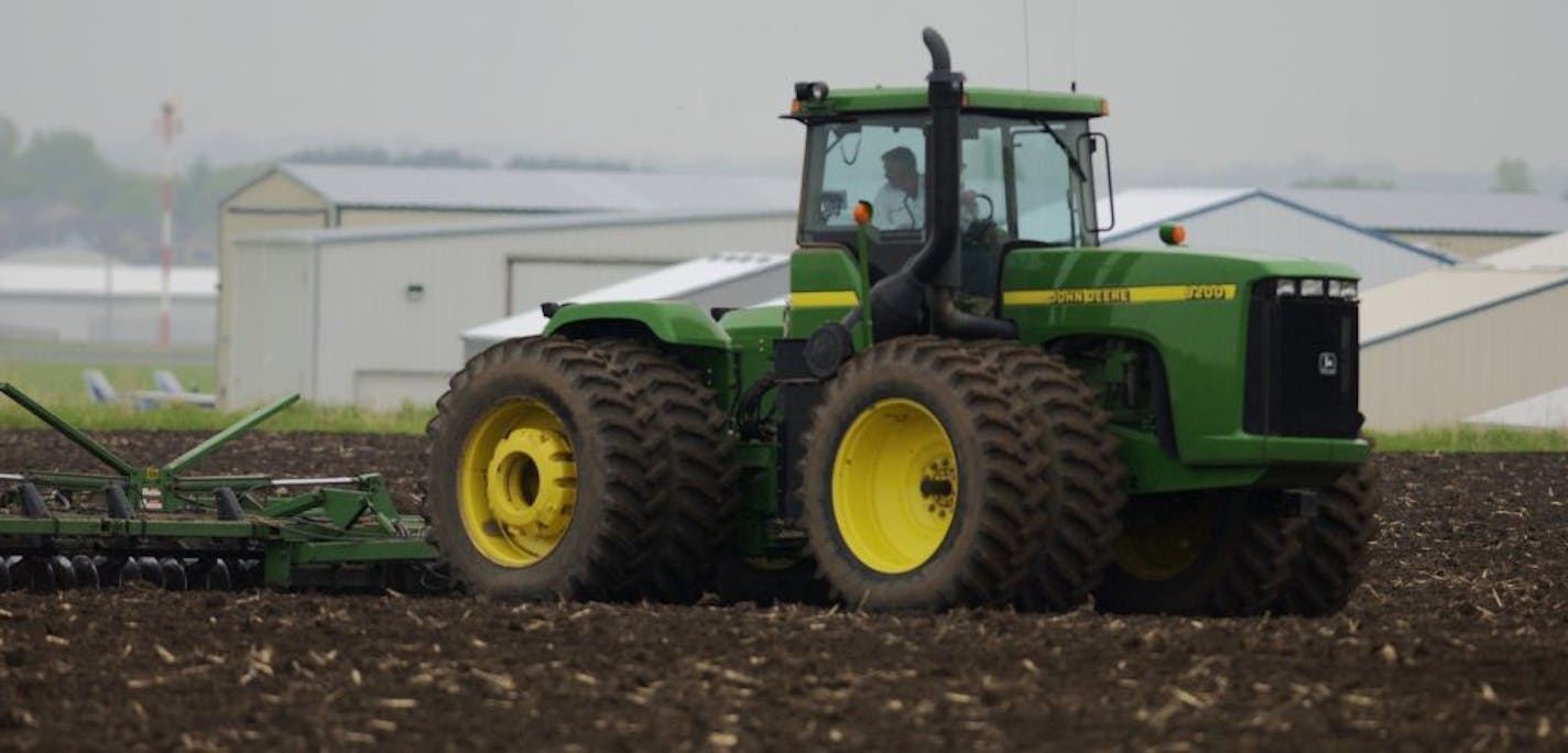 THURSDAY_05/22/03_Lake Elmo - - - - - - - - Peter Schiltgen prepareing the field for soybean planting, the Lake Elmo Airport facility is in background.