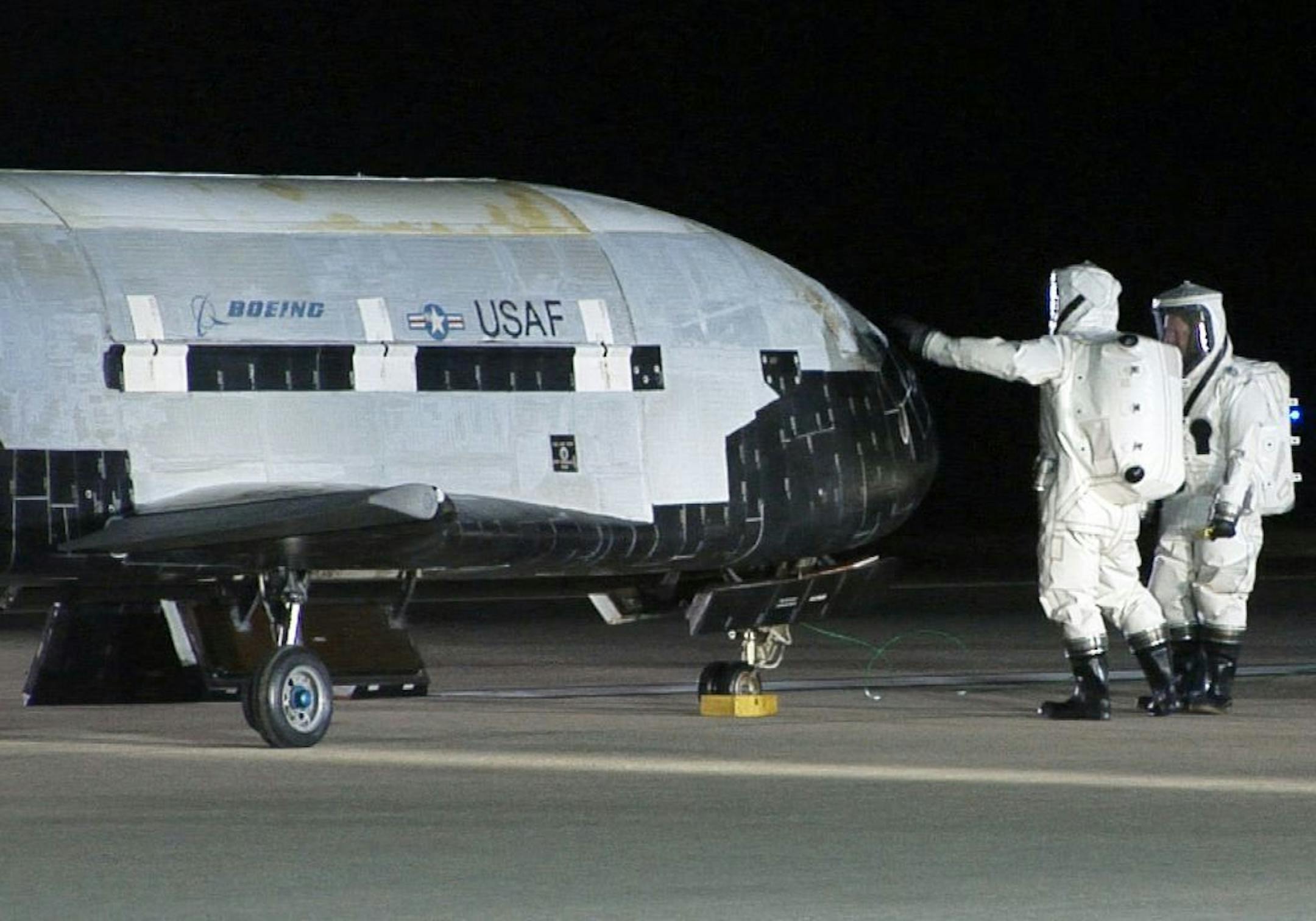 FILE - In this Dec. 3, 2010, file image provided by the Vandenberg Air Force Base shows technicians examining the X-37B unmanned spaceplane shortly after landing at Vandenberg Air Force Base, Calif. The military's small, top-secret version of the space shuttle is expected to land again at a Southern California Air Force base. The X-37B's mission is classified, only fueling speculation about why it was orbiting Earth for nearly two years.