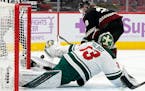Minnesota Wild goaltender Cam Talbot, bottom, makes a save on a shot from Arizona Coyotes left wing Dryden Hunt during the first period of an NHL hock