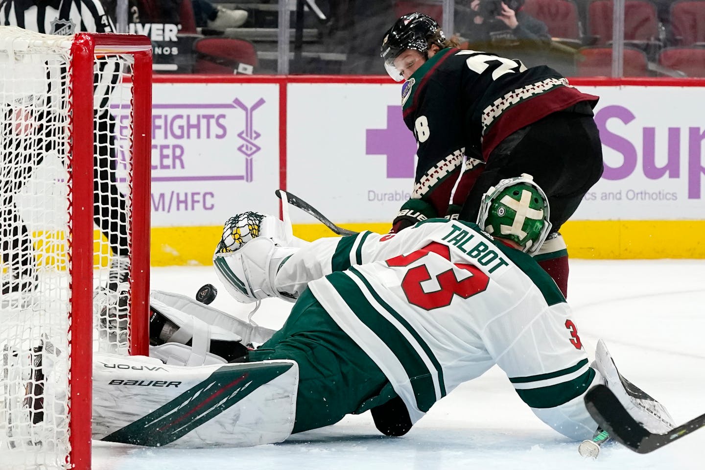 Minnesota Wild goaltender Cam Talbot, bottom, makes a save on a shot from Arizona Coyotes left wing Dryden Hunt during the first period of an NHL hockey game Monday, April 19, 2021, in Glendale, Ariz. (AP Photo/Ross D. Franklin)