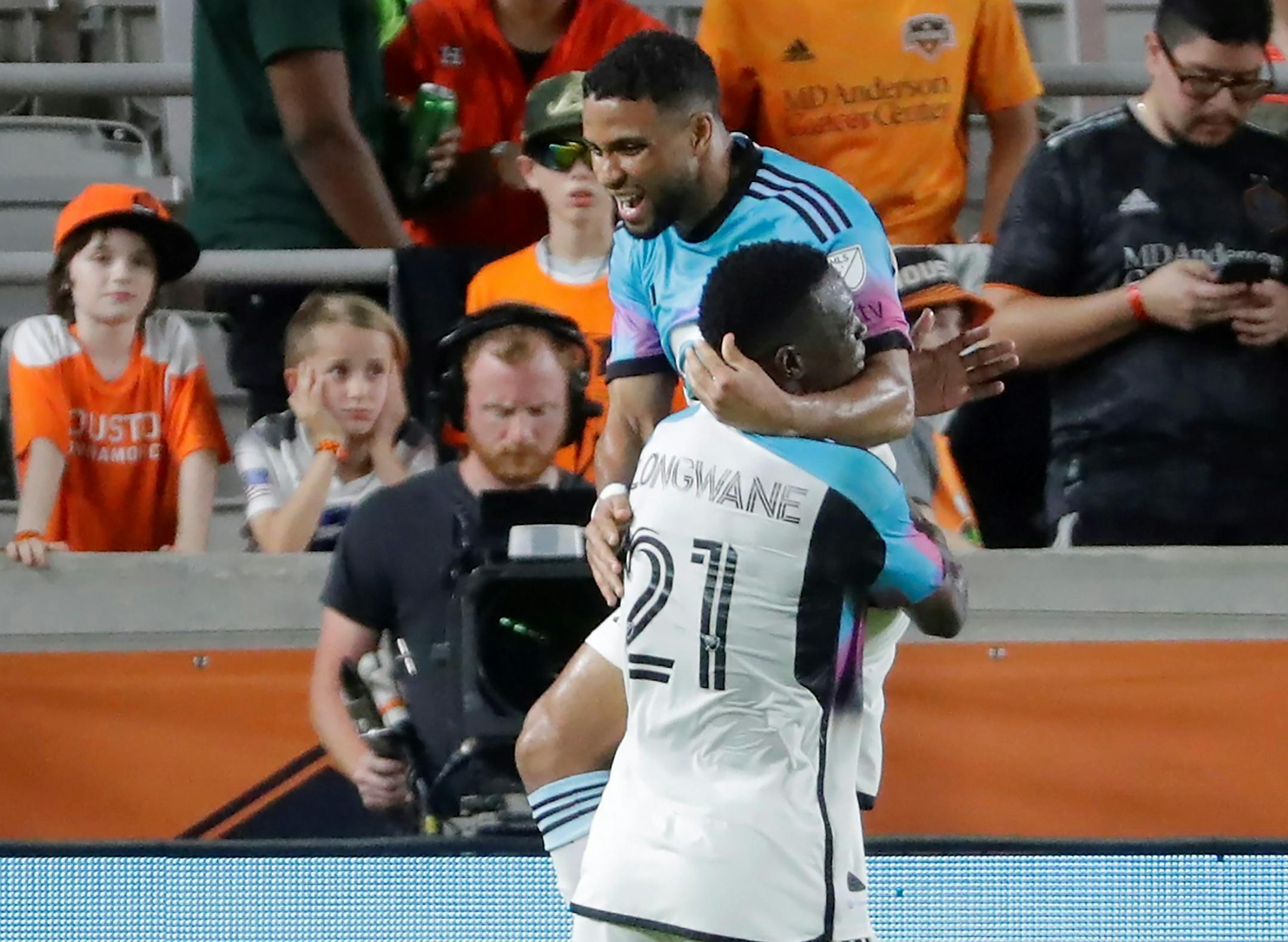 Minnesota United forwards Bongokuhle Hlongwane (21) and Ismael Tajouri-Shradi, top, celebrate the goal by Tajouri-Sharadi against the Houston Dynamo during the second half of an MLS soccer match Wednesday, July 12, 2023, in Houston. (AP Photo/Michael Wyke)
