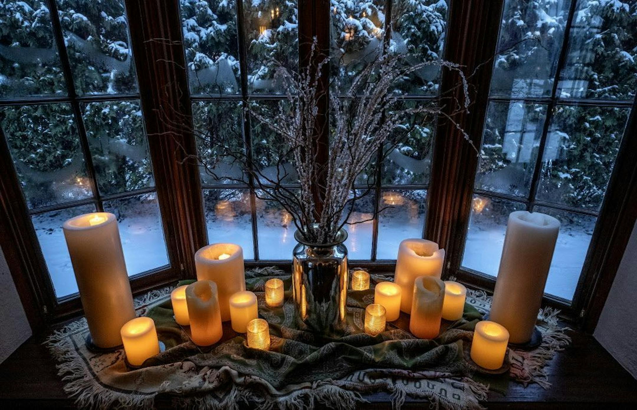 The candle vignette includes a mercury glass vase filled with ice crystal branches and throws gathered at the base.