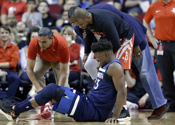 Minnesota Timberwolves guard Jimmy Butler (23) reacts to a knee injury on the court as Houston Rockets guard Chris Paul (3) and team trainers hover ov