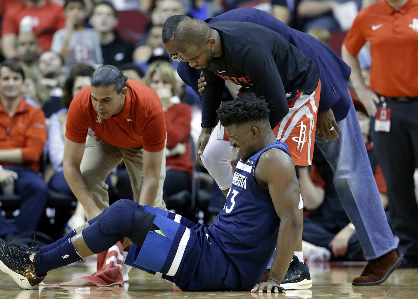 Minnesota Timberwolves guard Jimmy Butler (23) reacts to a knee injury on the court as Houston Rockets guard Chris Paul (3) and team trainers hover over him during the second half of an NBA basketball game Friday, Feb. 23, 2018, in Houston. (AP Photo/Michael Wyke)