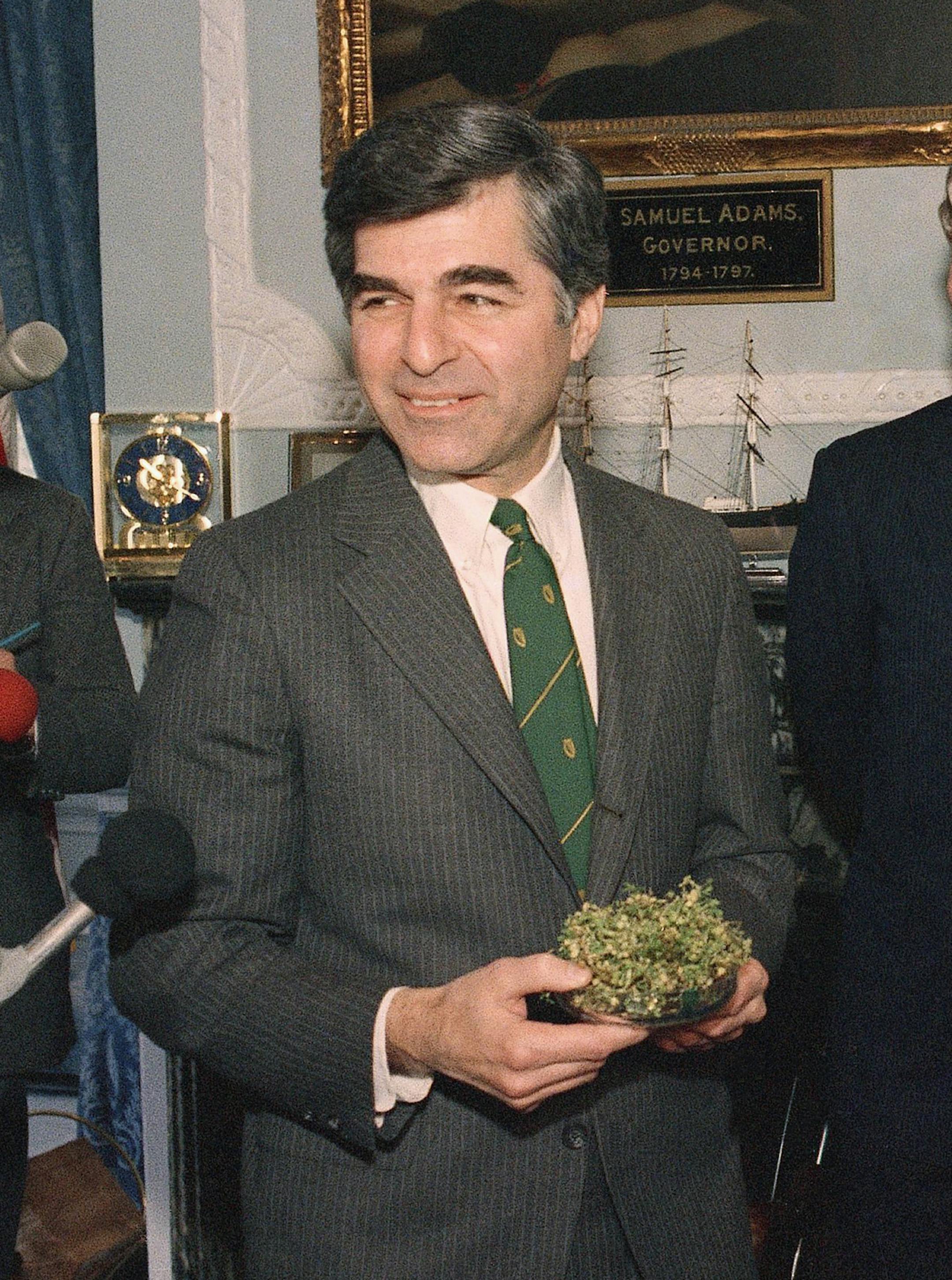 Massachusetts Governor Michael S. Dukakis, left, holds a bowl of shamrocks presented to him by the Irish Consul General Patrick Curran, center, and Breda O?Mahoney of the Irish airline Aer Lingus at his office on Tuesday, March 17, 1987 at the Statehouse in Boston. The presentation was made in honor of St. Patrick?s Day and a bit of Irish luck might help Dukakis in his intended bid for the 1988 Democratic presidential nomination. (AP Photo/Mark Lennihan)