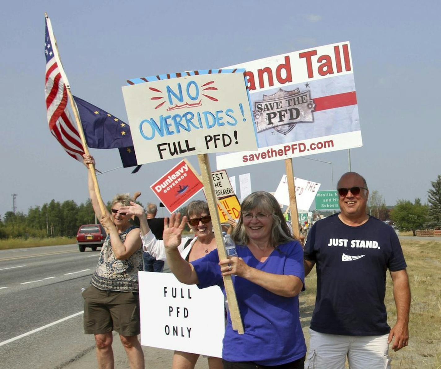 FILE - In this July 8, 2019 file photo, supporters of a fully funded oil check hold signs in Wasilla, Alaska. For decades, Alaska has had an uneasy reliance on oil, building budgets around its volatile boom-or-bust nature. When times were rough, prices always seemed to rebound, forestalling a day of reckoning some believe may finally have come. The situation has politicians weighing changes to the annual dividend paid to residents from earnings of the state's oil-wealth fund, the Alaska Permanen