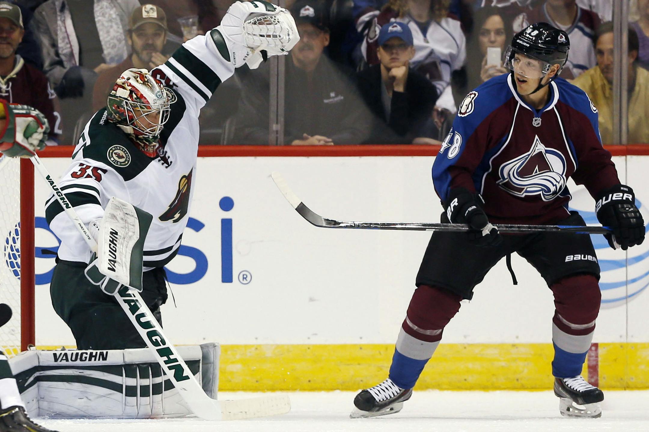 Minnesota Wild goalie Darcy Kuemper, left, makes a glove save of a redirected shot off the stick of Colorado Avalanche center Daniel Briere in the first period of a hockey game in Denver on Saturday, Oct. 11, 2014. (AP Photo/David Zalubowski)