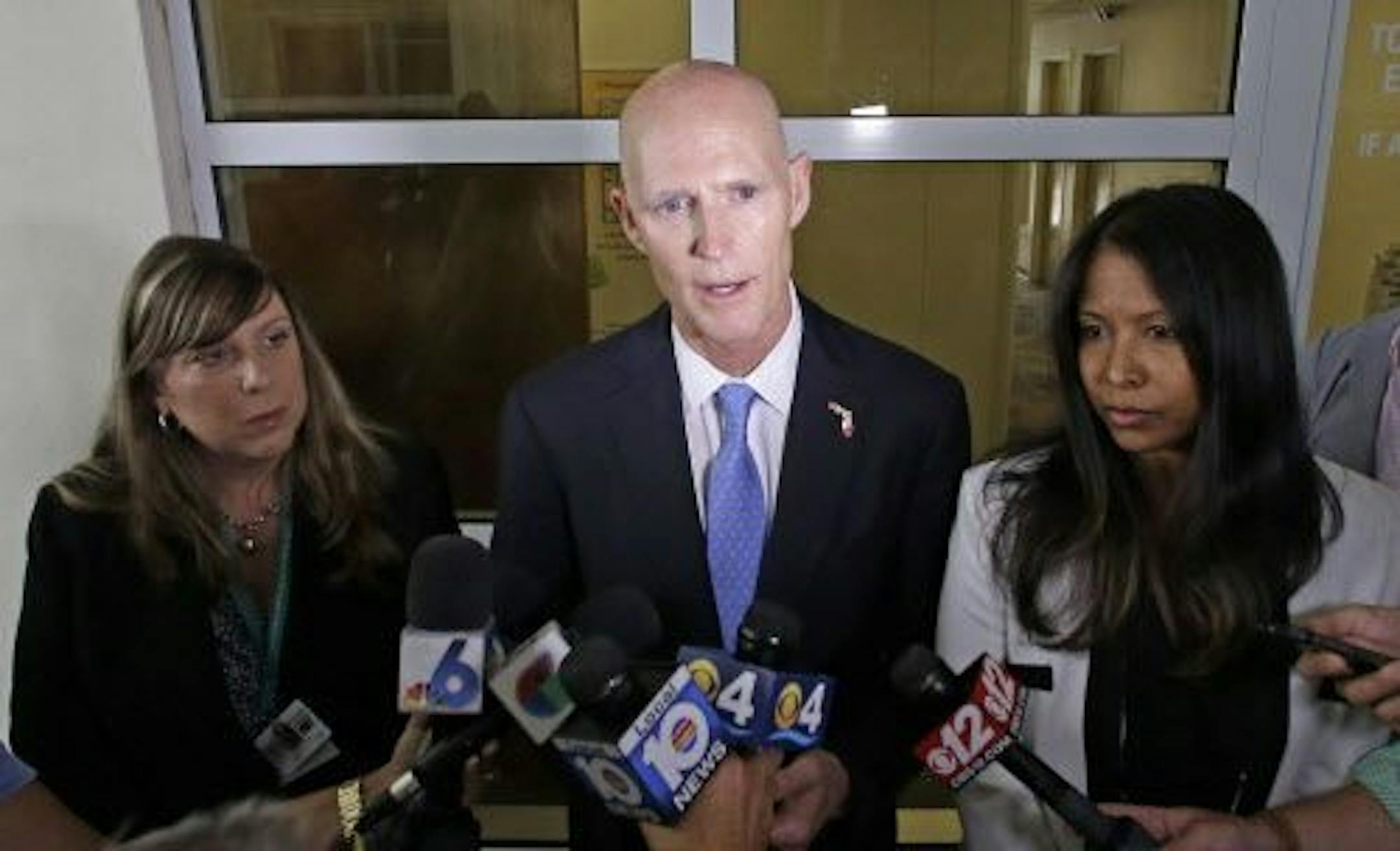 Gov. Rick Scott, center, flanked by Dr. Paula Thaqi, Director of the Broward County Health Department, left, and Dr. Celeste Philip, State Surgeon General, right, talks to reporters after a meeting with community leaders, at the Broward County Health Department, Tuesday, July 26, 2016, in Fort Lauderdale, Fla.