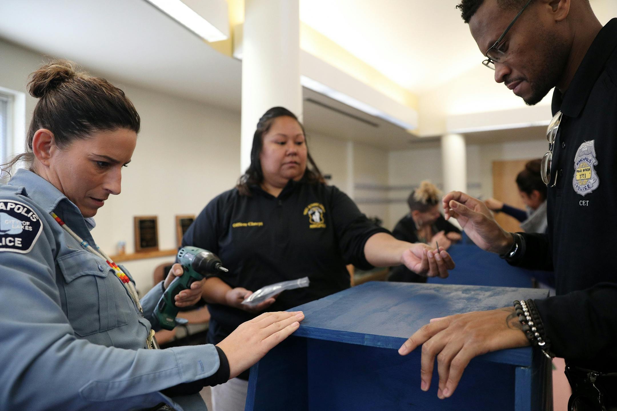 Police officers Colleen Saunby, left, Cheryl Goodman, center, and Jon Edwards, right, worked to build free-standing Little Free Libraries Tuesday.