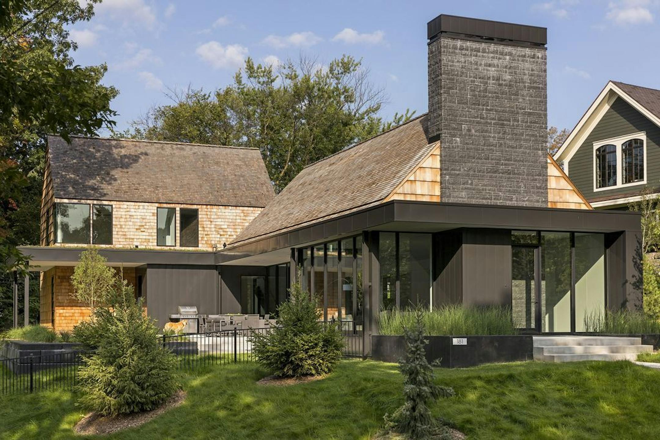 Warm textural cedar shakes are juxtaposed with cool expanses of glass and a stone chimney.