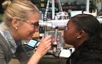 Optometrist Dr. Meredith Walburg examines Denae Whitfield's eyes at Harding High School. Whitfield is one of 2,500 St. Paul Public Schools students sc