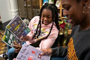 Malia Stanley and Brianna Johnson read the newly-published “Kings of Quests: A Tale of Bros” before the seventh-grade author Miles Asberry-Wallace