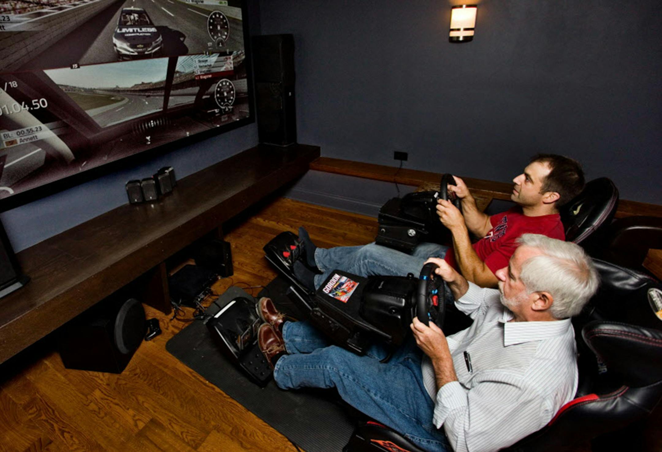 Matt Wagoner, in red shirt, of Limitless Construction, and friend Tom Sweeney try out the NASCAR simulator that Wagoner installed in the theater of a St. Louis Park house he remodeled.