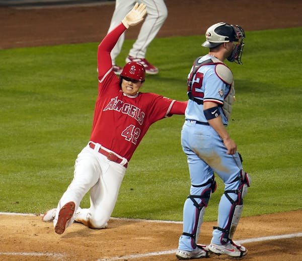 Shohei Ohtani of the Angels slid past Twins catcher Mitch Garver to score Friday night.