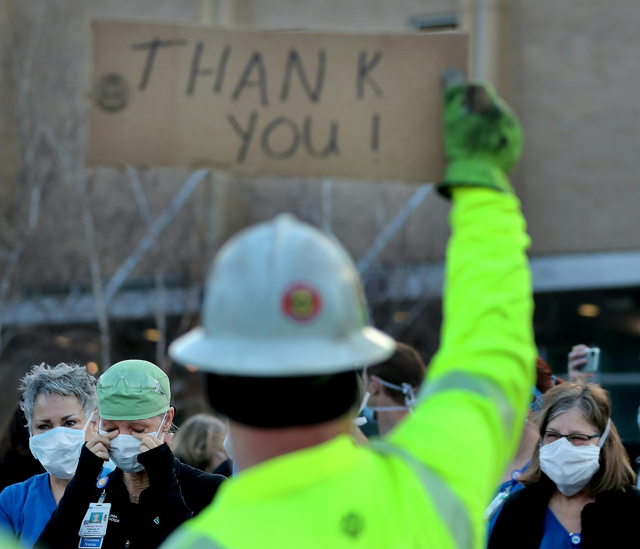 Healthcare workers at Regions Hospital came outside the hospital, including Tamara Hill, an ER RN, seen wiping away tears, to thank Xcel Energy crew members, including Paul Peikert, who had lined the street outside Regions to greet healthcare workers during the early morning shift change outside Regions Hospital Wednesday, April 22, 2020 in St. Paul, MN.