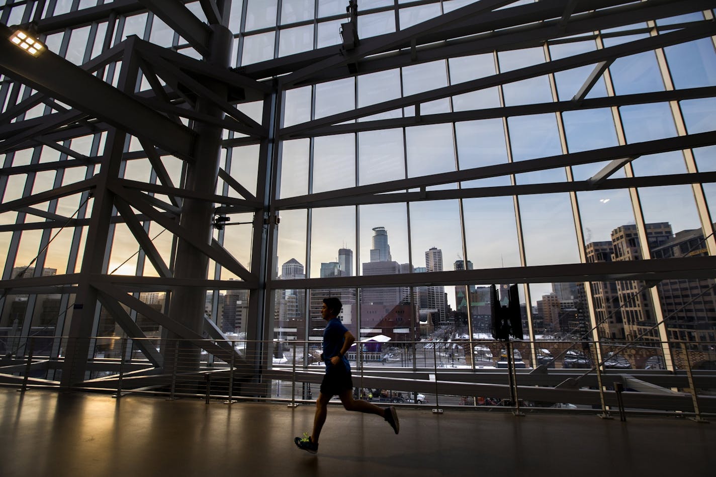 A runner goes past the downtown skyline as the sun sets while running inside U.S. Bank Stadium in 2018.