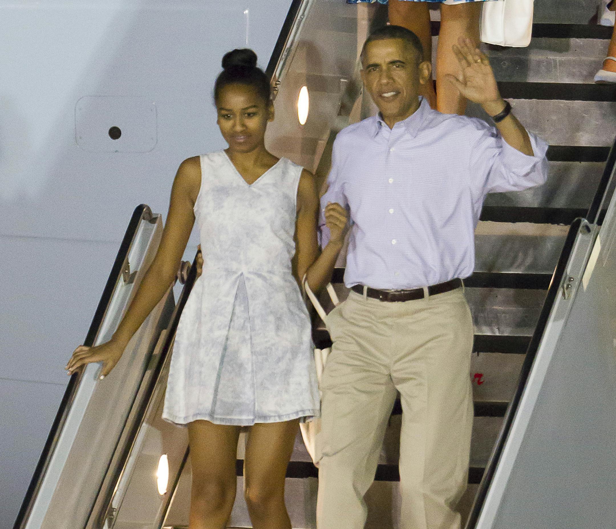 President Barack Obama, right, with his daughter Sasha, bottom left, the first lady Michelle Obama, top left center, and their other daughter Malia top right, disembark Air Force One after arriving at Joint Base Pearl Harbor-Hickam for their annual family Christmas vacation Friday, Dec. 19, 2014, in Honolulu. The first family will be staying in Kailua, Hawaii. (AP Photo/Eugene Tanner)