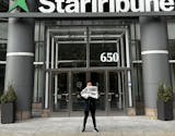 Jon Cheng standing in front of the Star Tribune's downtown Minneapolis office holding a paper with his debut restaurant review.