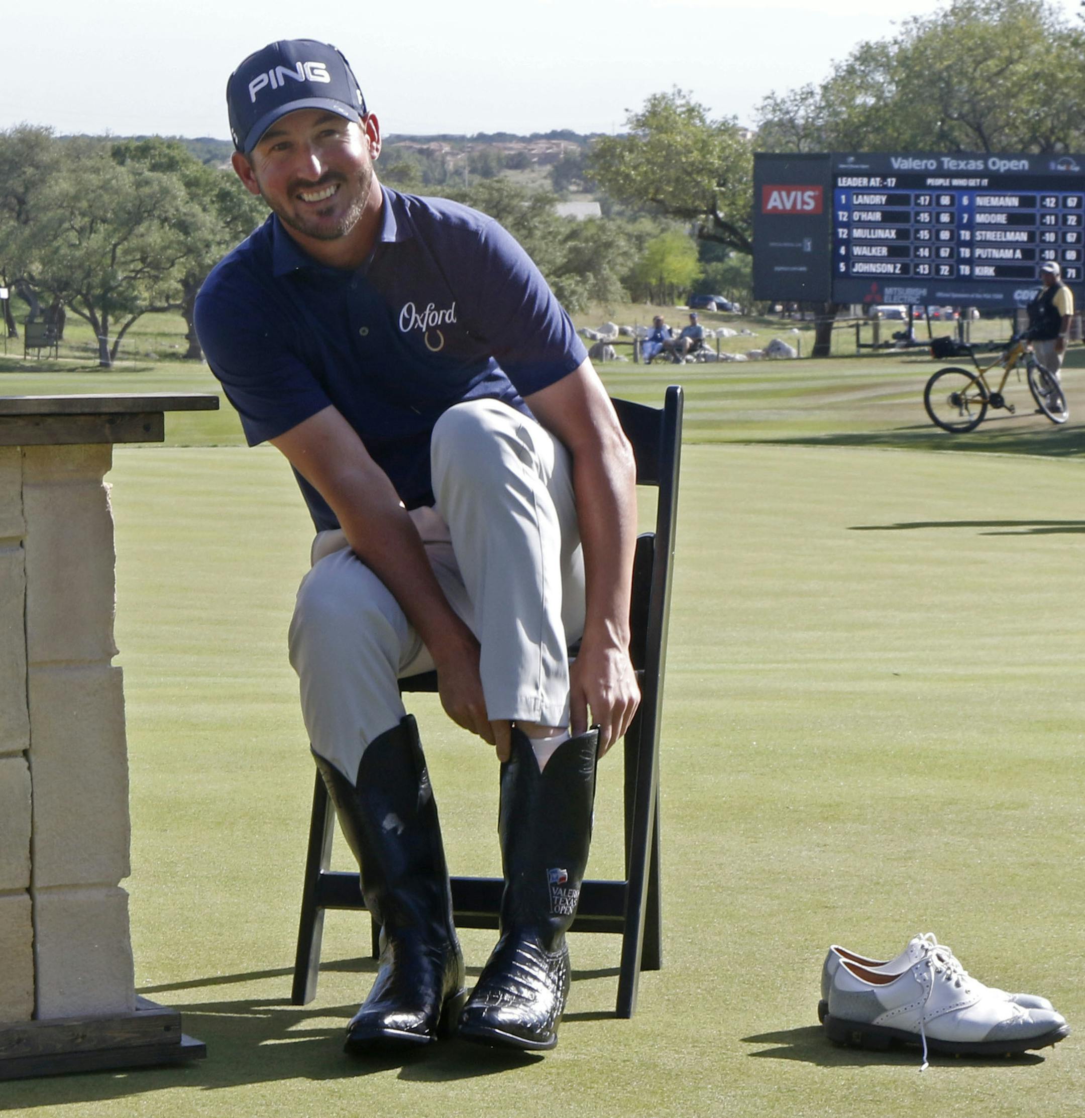 Andrew Landry puts on boots given to the winner of the Valero Texas Open golf tournament, Sunday, April 22, 2018, in San Antonio. Landry won with a score of 17 under par. (AP Photo/Michael Thomas)