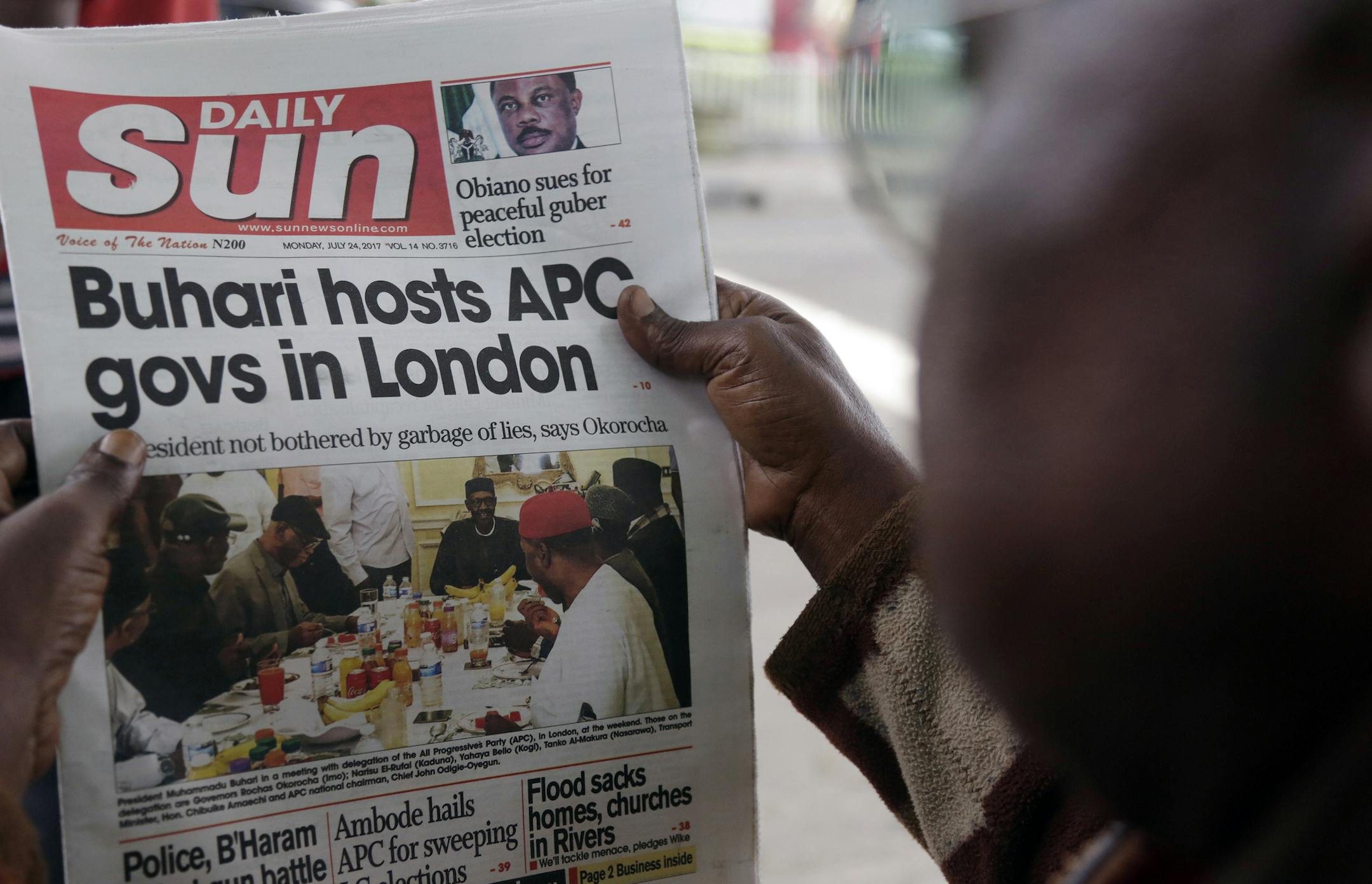 FILE - In this Monday, July. 24, 2017 file photo, a man reads a story about Nigeria's President Muhammadu Buhari after the government released a photo of Buhari more than two months after he left for London for medical treatment, in Lagos, Nigeria. In Nigeria and other African countries fighting fake news is vexing and divisive, especially as major elections loom. (AP Photo/Sunday Alamba, File) ORG XMIT: NAI501