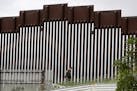 In this March 18, 2020, photo, a Border Patrol agent walks along a border wall separating Tijuana, Mexico, from San Diego. President Donald Trump has 