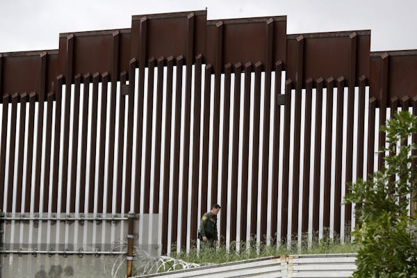 In this March 18, 2020, photo, a Border Patrol agent walks along a border wall separating Tijuana, Mexico, from San Diego. President Donald Trump has 