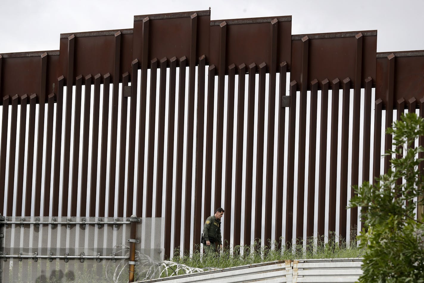 In this March 18, 2020, photo, a Border Patrol agent walks along a border wall separating Tijuana, Mexico, from San Diego. President Donald Trump has succeeded in fundamentally transforming the nation's immigration system, despite resistance from the courts and little cooperation from Congress.