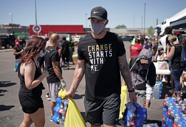 Kyle Rudolph helps a woman carry items to her car during a food distribution event last Friday in Minneapolis.