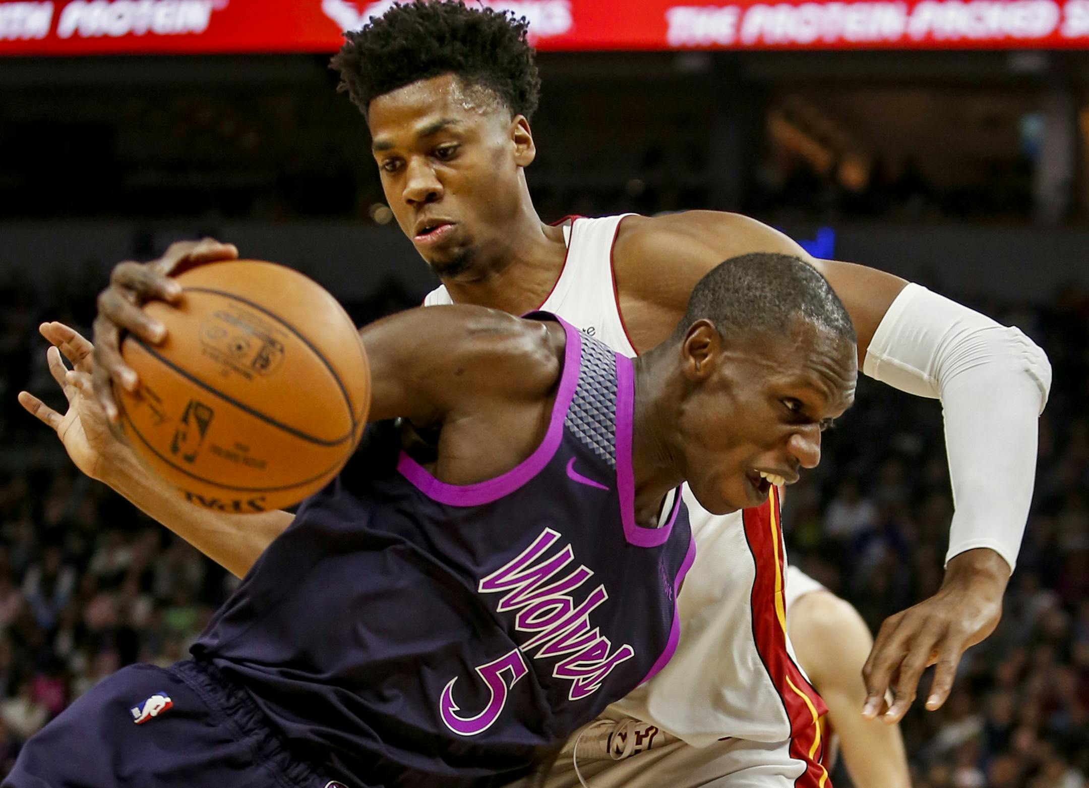 Minnesota Timberwolves center Gorgui Dieng (5) drives to the basket around Miami Heat center Hassan Whiteside, top, in the second quarter of an NBA basketball game Friday, April 5, 2019, in Minneapolis. (AP Photo/Bruce Kluckhohn)
