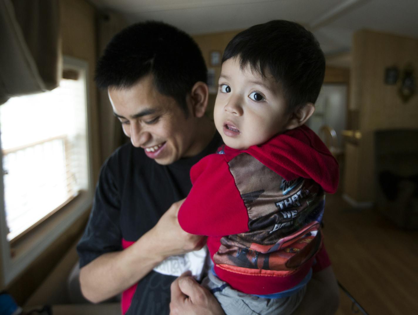 Fabian Segarra stands inside his home with his 14-month-old son Steben. ] (Leila Navidi/Star Tribune) leila.navidi@startribune.com BACKGROUND INFORMATION: Thursday, April 28, 2016. Fabian Segarra and his family bought a manufactured home in Lowry Park for $25,000 in August 2015 and has made $5,000 worht of improvements to the property since then. The owner of Lowry Grove, a manufactured home and RV park that is home to 100 families in St. Anthony, has received an offer to sell the park. Pending