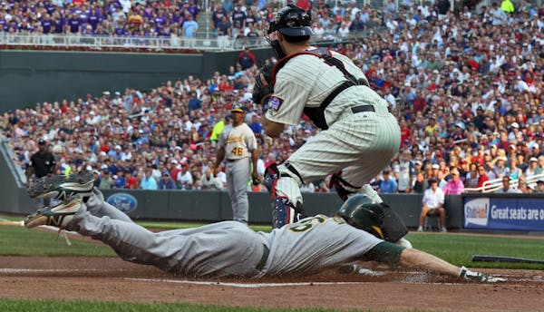 Minnesota Twins vs. Oakland Athletics. Oakland's Josh Reddick slid saflely into home beating the throw to Twins catcher Joe Mauer for the first run of