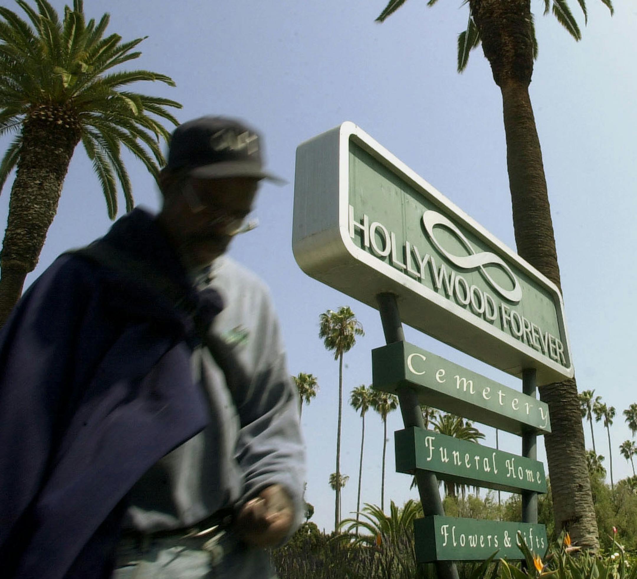 FILE- In this May 5, 2002, file photo, a passerby strolls past the entrance of Hollywood Forever Cemetery in Los Angeles. Judy Garland's remains were moved cross-country to a mausoleum intended as the resting place for daughters Liza Minnelli and Lorna Luft and other family members. The transfer from a crypt in New York's Ferncliff Cemetery to Hollywood Forever Cemetery was completed last Friday, Jan. 27, 2017, Noelle Berman, a Hollywood Forever spokeswoman, told The Associated Press. (AP Photo/