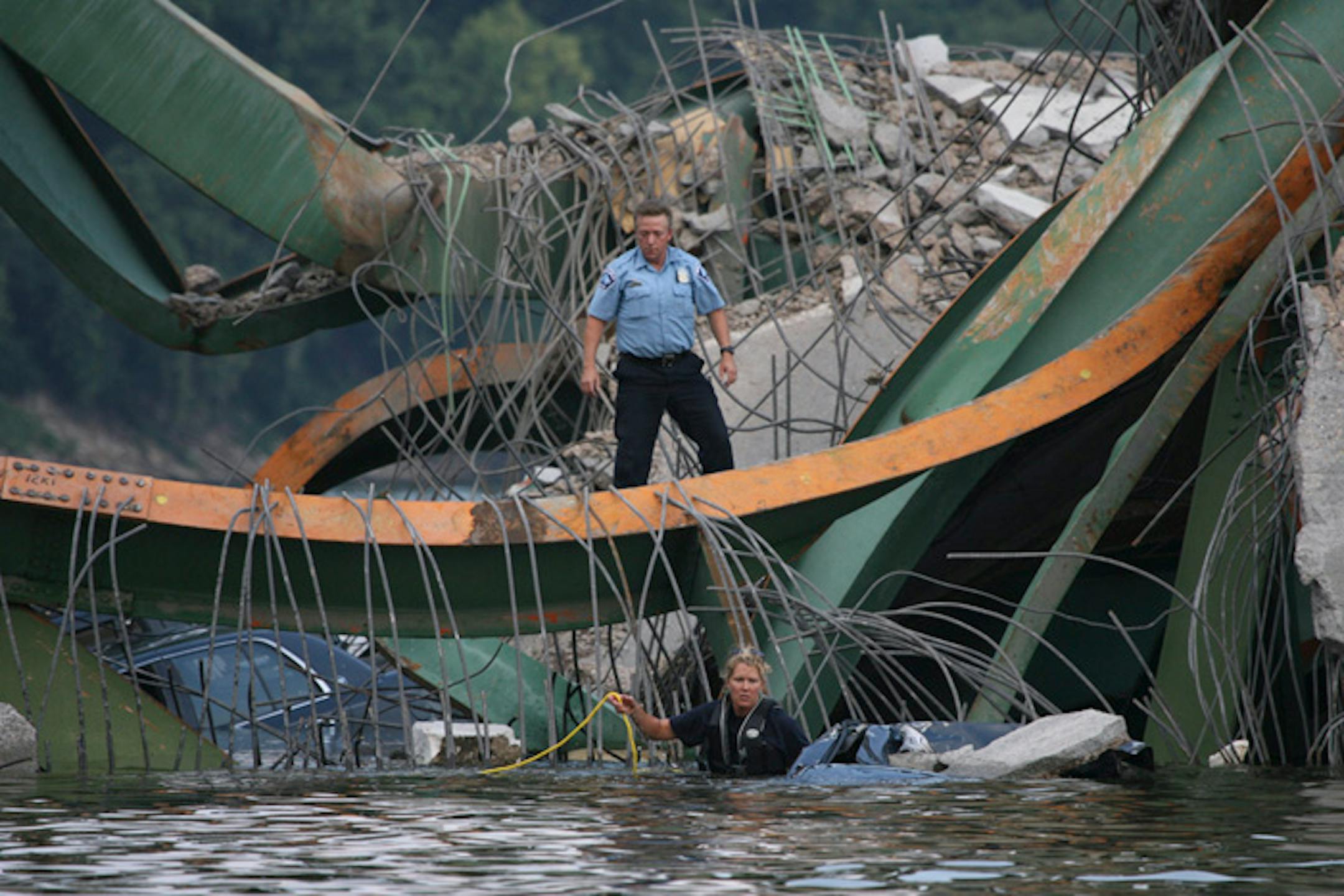 A rescue worker stood ready while another prepared to search a submerged vehicle after the Interstate 35W bridge in Minneapolis spanning the Mississippi River collapsed on Aug. 1, 2007.