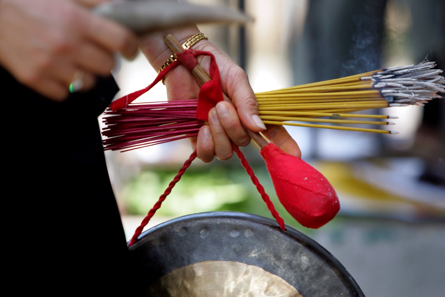 A shaman's tools: Incense, ox horn and gong. Mai Yang also used paper with swatches of bright red and gold that resembled money to coax the souls out of the building and back to their graves. Using her gong and money, Yang was able to help them leave. As the incense burned in a tin outside the funeral home, Yang stood on the stoop, facing the door. She chanted and sealed the building from any spirits returning.