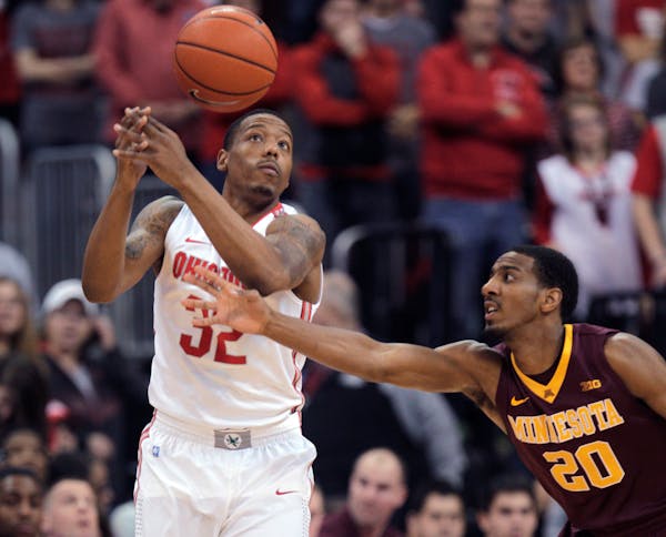 Minnesota's Austin Hollins, right, tips the ball away from Ohio State's Lenzelle Smith during the first half of an NCAA college basketball game Saturd
