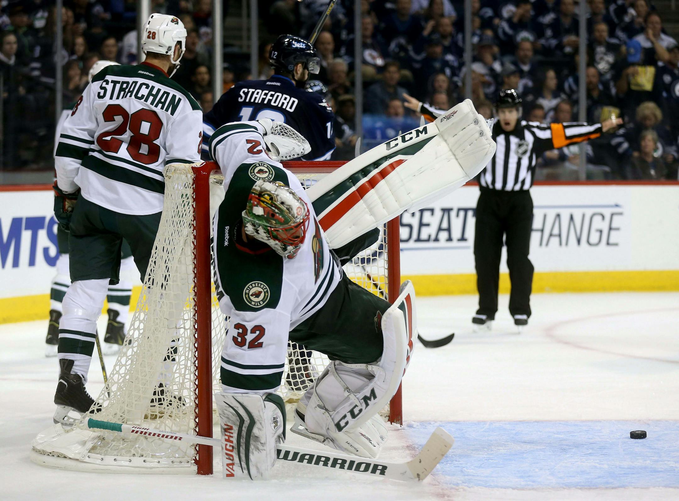 Minnesota Wild goaltender Niklas Backstrom, center, hangs onto the net after being pushed backwards by a Winnipeg Jets player during the second period of an NHL preseason hockey game Tuesday, Sept. 22, 2015, in Winnipeg, Manitoba. (Trevor Hagan/The Canadian Press via AP) MANDATORY CREDIT