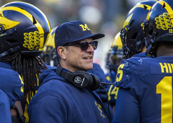 FILE - In this Nov. 16, 2019, file photo, Michigan head coach Jim Harbaugh huddles with his players on the field during a time out in the fourth quart