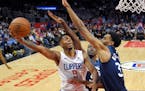 Clippers guard Tyrone Wallace, left, shoots as Timberwolves center Gorgui Dieng, center, and forward Keita Bates-Diop defend during the second half We