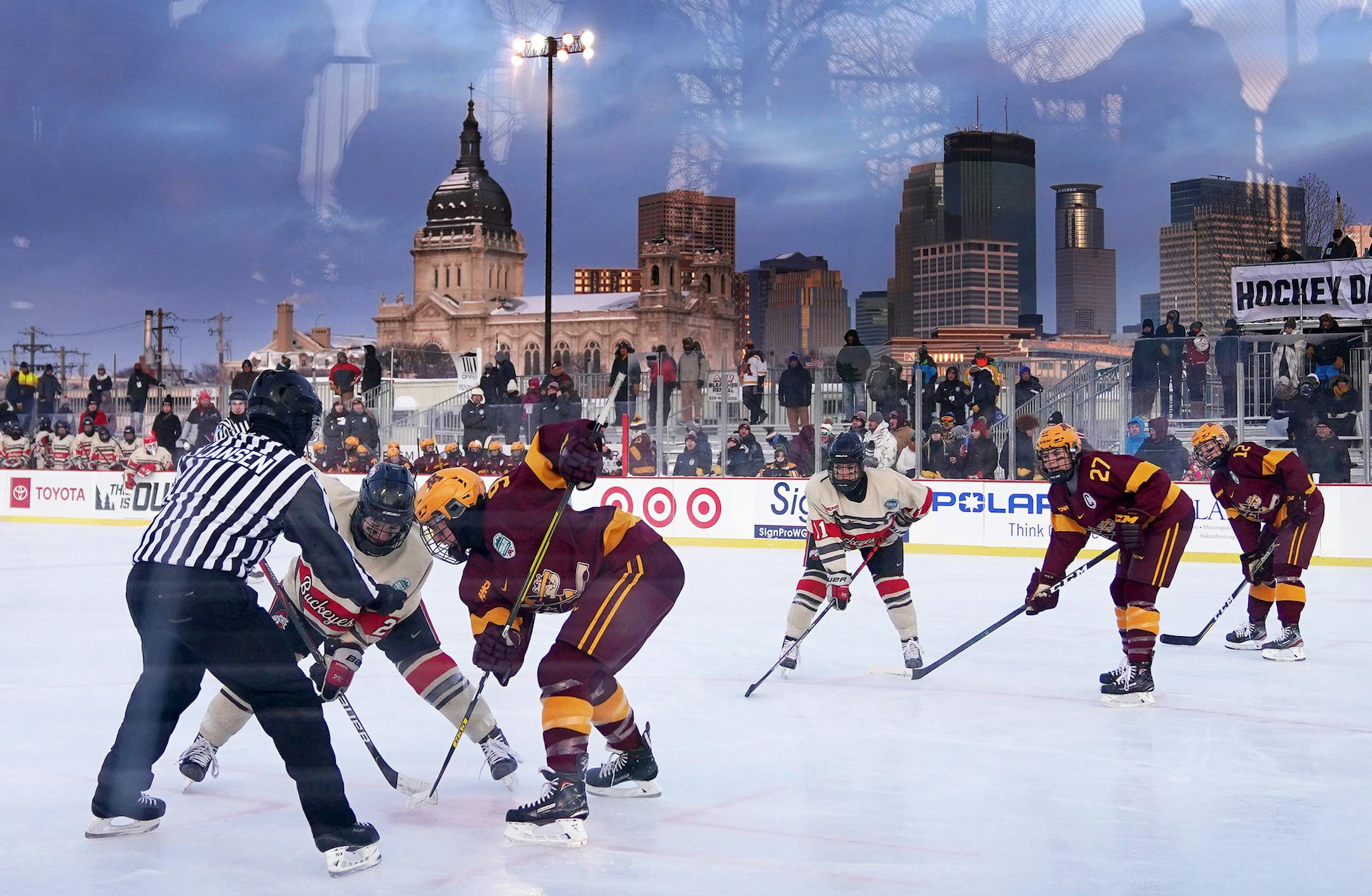 Hockey fans were reflected in the glass as Minnesota forward Taylor Heise (9) took a face off against Ohio State forward Liz Schepers (21) in the first period of Saturday's game on Minnesota Hockey Day at Parade Stadium.