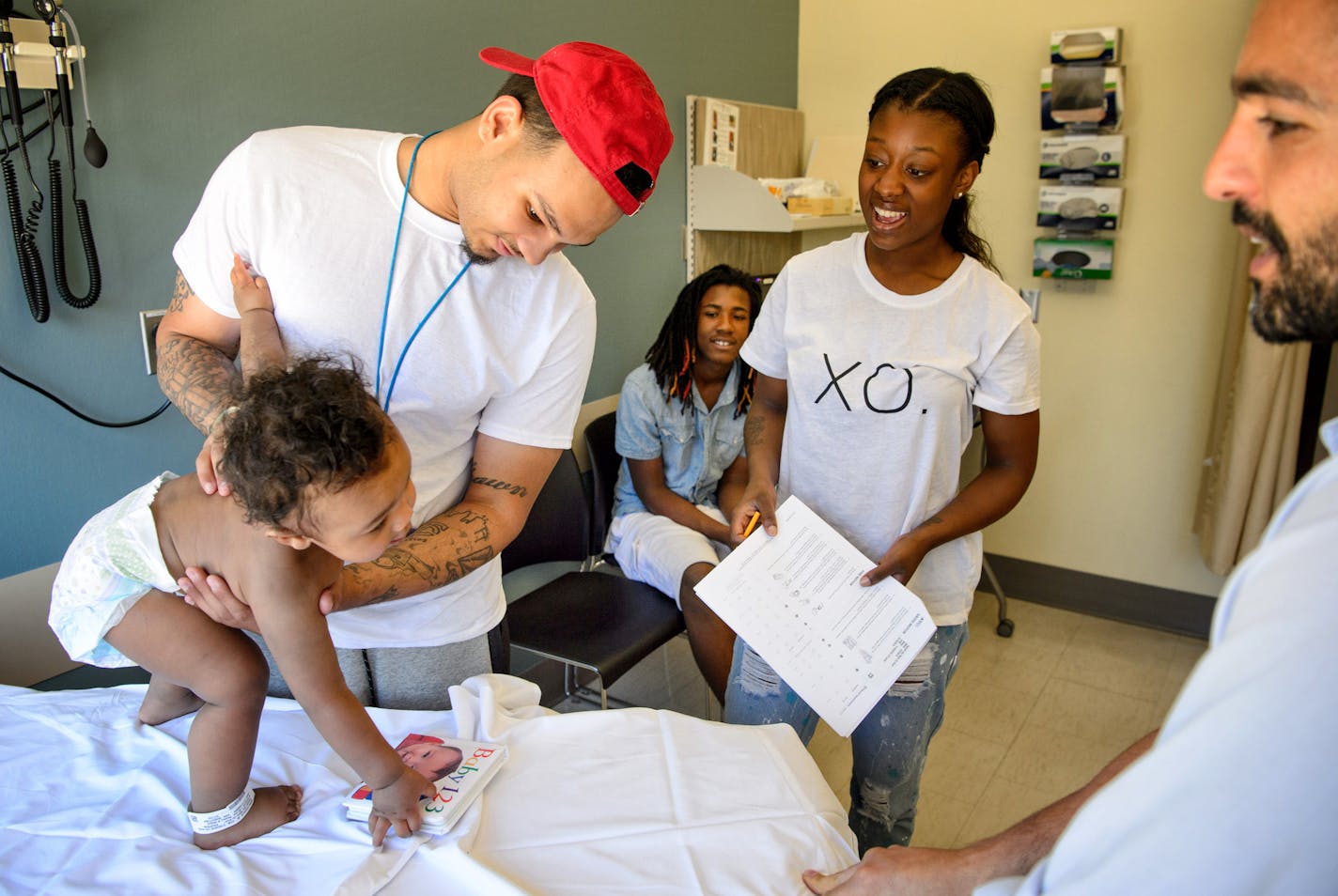 Pediatrician Dr. Rhamy Magid, right, watched as 10-month-old Kar&#x2019;melo Teetzel reached to pick up a book during his checkup.