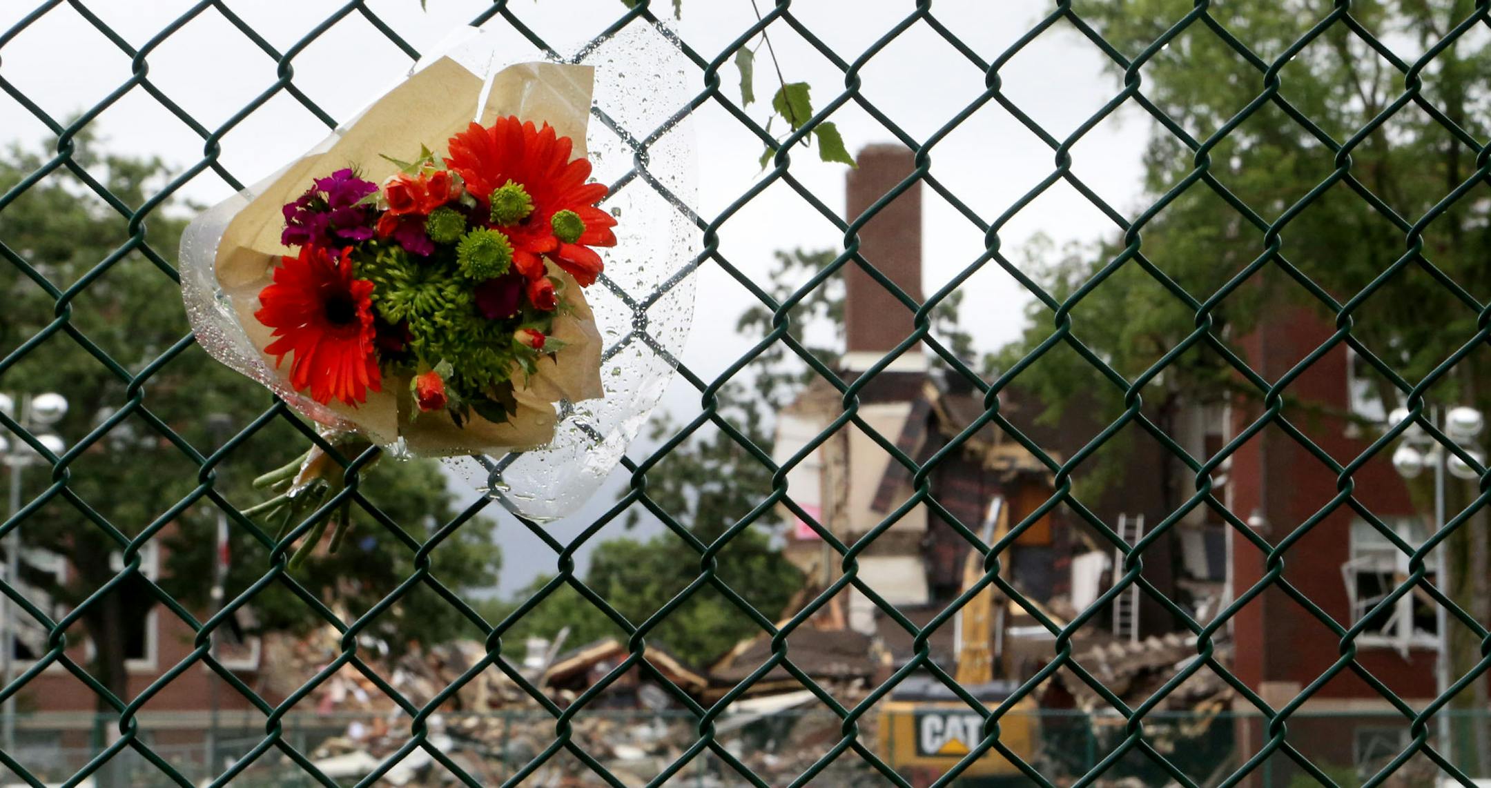 A day after an explosion and building collapse at Minnehaha Academy that left two dead and several injured, the scene was quiet as light rain fell and media members tried to stay dry Thursday, Aug. 3, 2017, in Minneapolis, MN. Here, Memorial flowers are wedged in the fence outside the Minnihaha Academy soccer field.] DAVID JOLES ï david.joles@startribune.com A day after an explosion and building collapse at Minnehaha Academy that left 2 dead and several injured, the scene was quiet as light