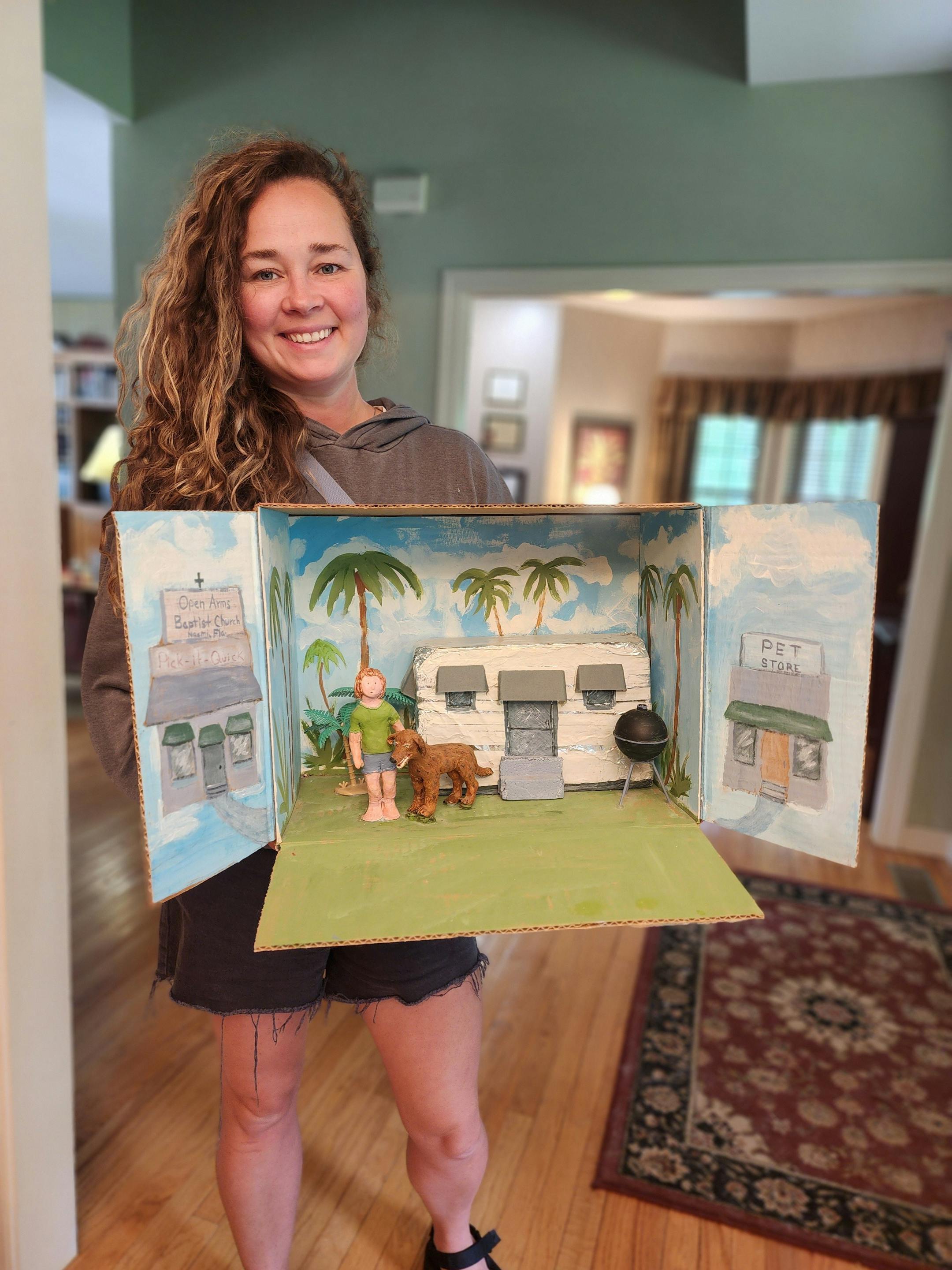 photo of woman holding "Because of Winn-Dixie" diorama that depicts a girl and a dog.