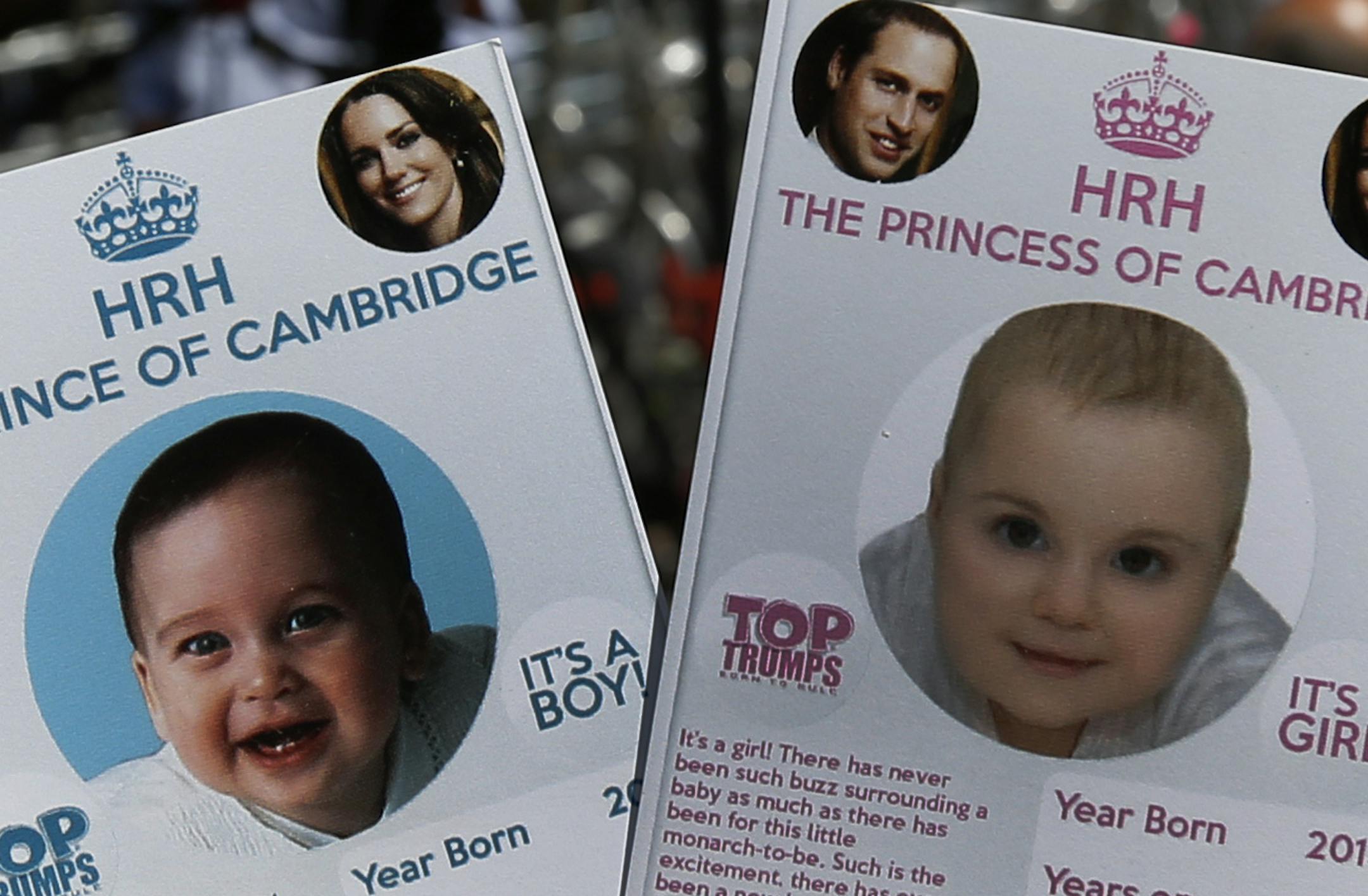 Cards depicting the 'royal baby' either as a boy or a girl, specially made by a games company as a publicity stunt are pictured, backdropped by members of the media waiting across the St. Mary's Hospital exclusive Lindo Wing in London, Thursday, July 11, 2013. Media are preparing for royal-mania as Britain's Duchess of Cambridge plans to give birth to the new third-in-line to the throne in mid-July, at the Lindo Wing. Cameras from all over the world are set to be jostling outside for an exclusiv