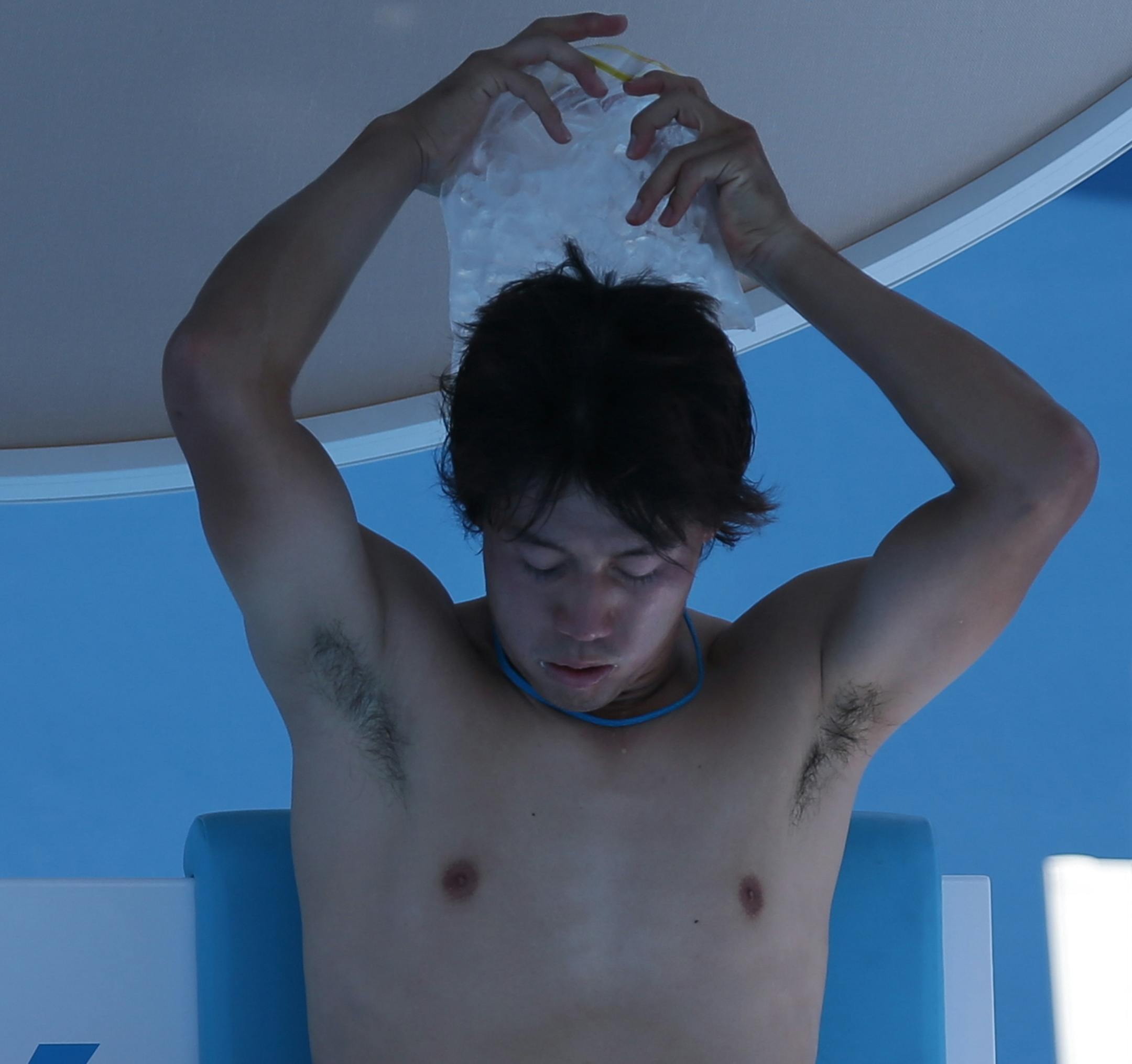 Kei Nishikori of Japan cools off with help of an ice pack during a break in the first round match against Marinko Matosevic of Australia at the Australian Open tennis championship in Melbourne, Australia, Tuesday, Jan. 14, 2014. (AP Photo/Aaron Favila)