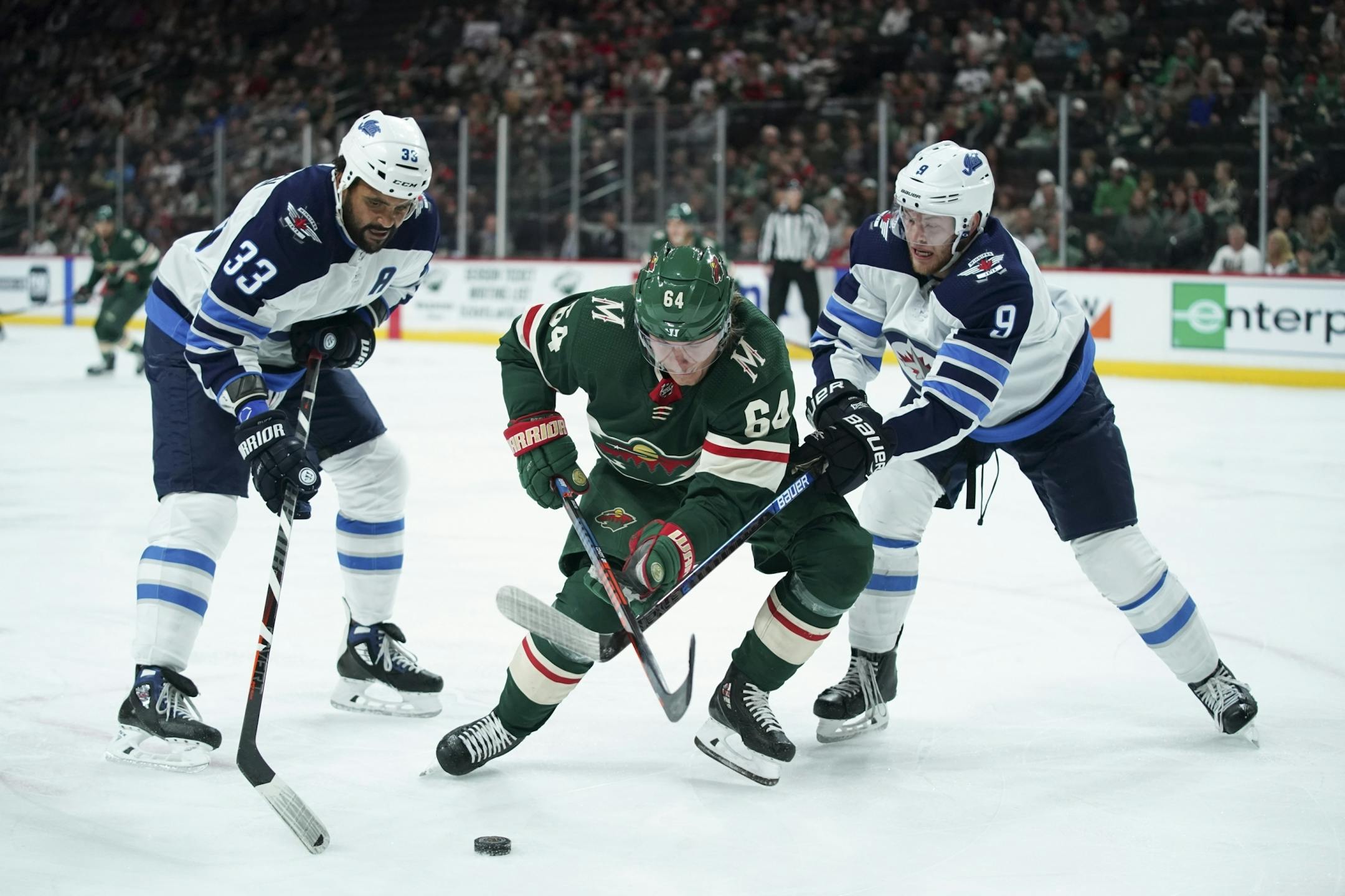 Minnesota Wild right wing Mikael Granlund (64) fought for the puck in the corner in the first period with Winnipeg Jets Dustin Byfuglien (33) and Andrew Copp (9).