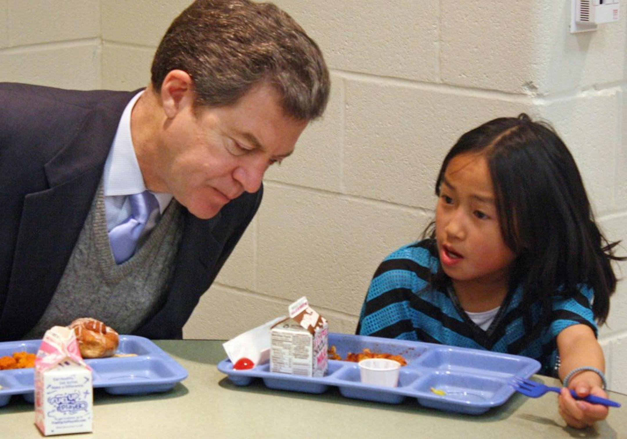 FILE - In this Jan. 23, 2014 file photo Kansas Gov. Sam Brownback, left, leans in to listen to Xen Hesse as the two each lunch at Roesland Elementary School in Roeland Park, Kan.