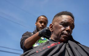 Mustafa Samatar cuts Milton Manning's hair behind Peace House community center in Minneapolis on Wednesday. A dozen barbers from Shifty's Premium Cuts