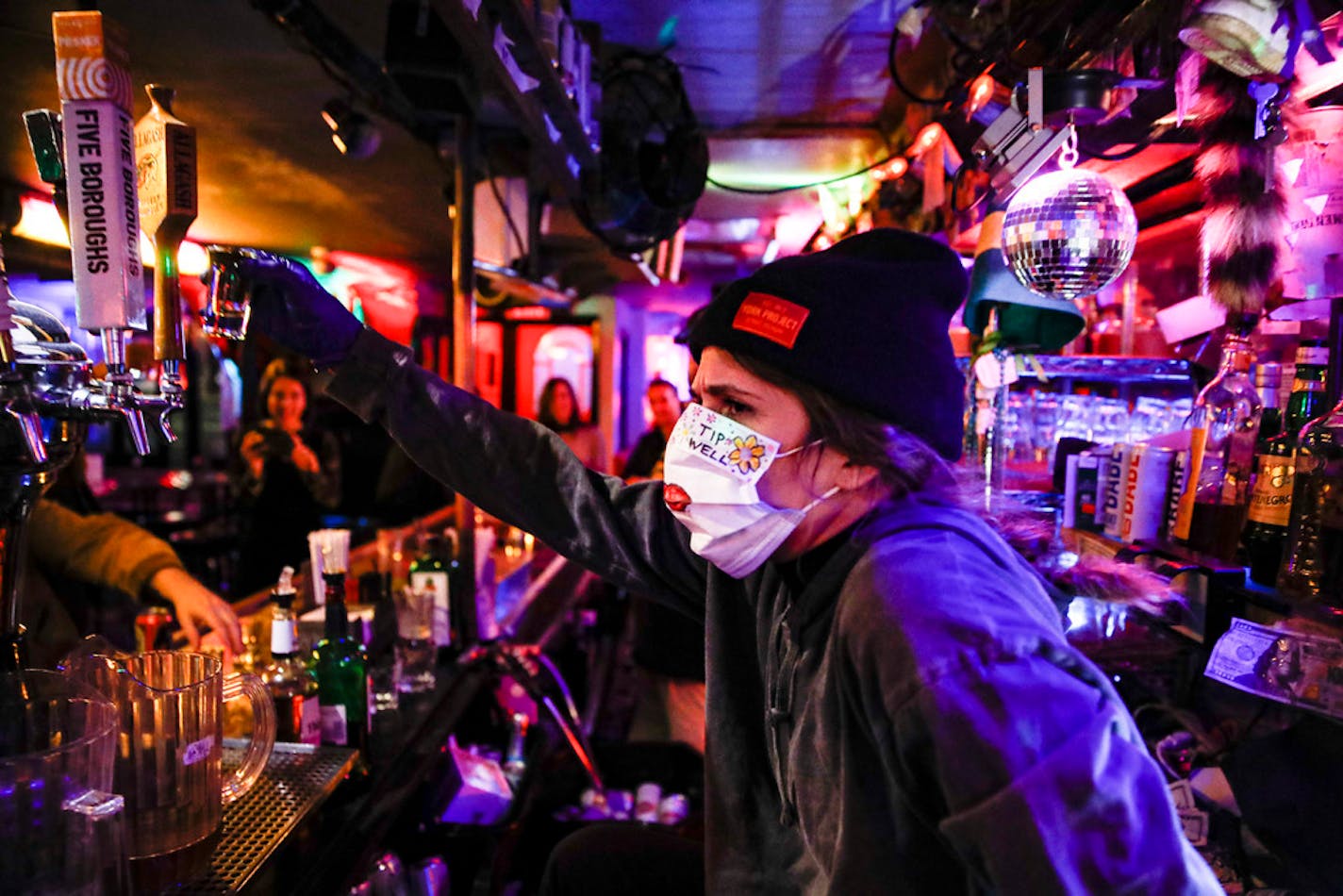 Bartender Cassandra Paris takes a farewell shot at an early closing time at 169 Bar with patrons, March 16, 2020, in New York.