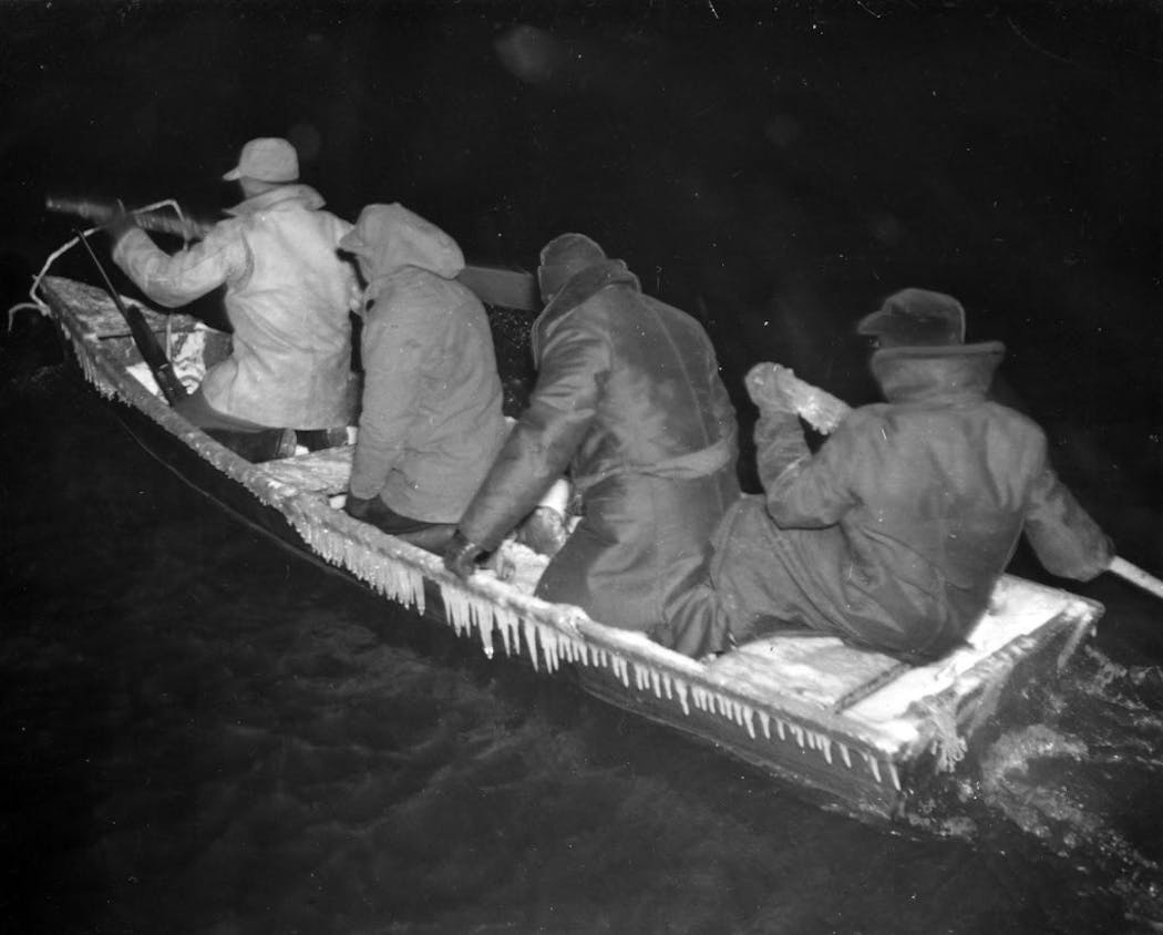 Four searchers ply the backwaters of the Misssissippi in a hunting skiff, combing the shores of the Mississippi River bottom lands, looking for hunters caught in the Armistice Day blizzard. November 1940 