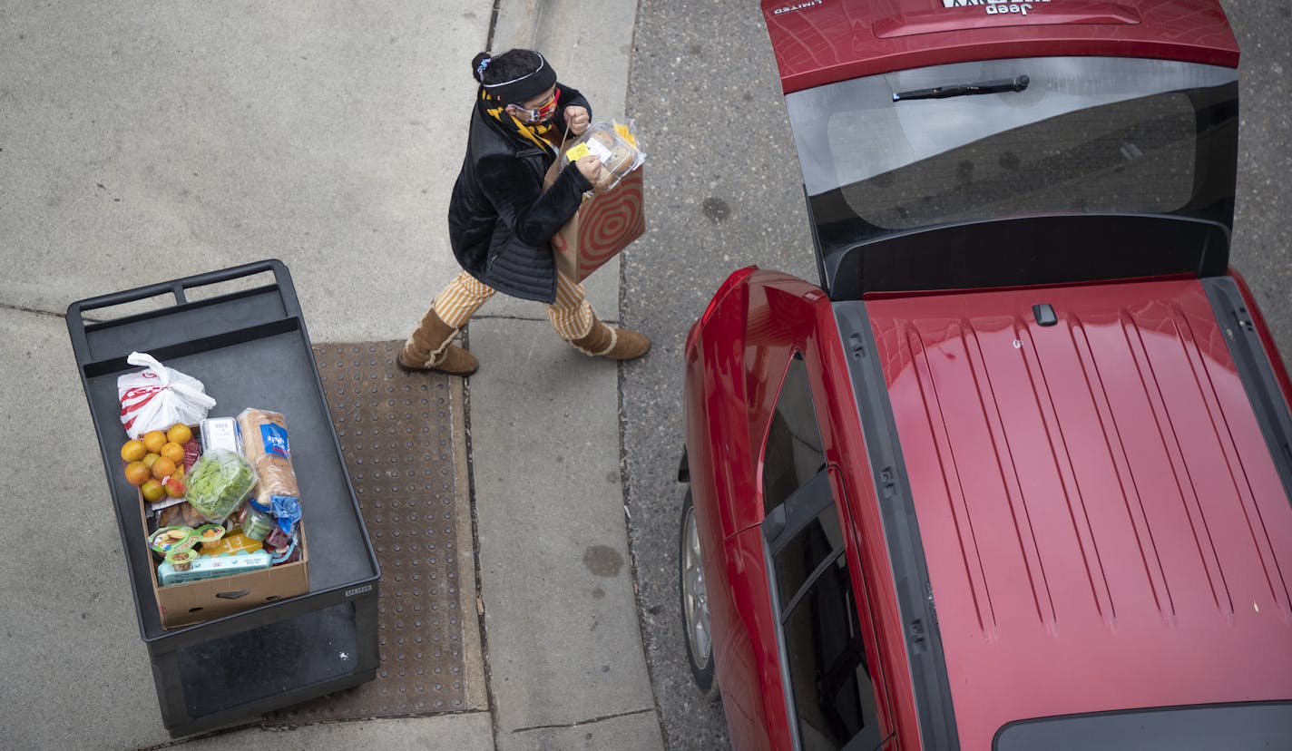 A Hennepin County resident carried a bag of groceries to her car that she received from CEAP in April in Brooklyn Center.